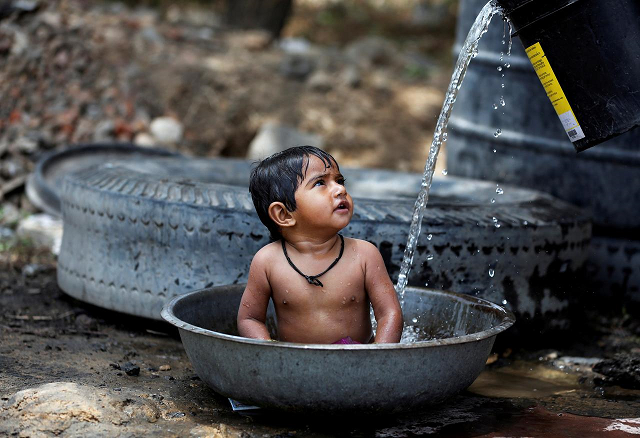 a baby girl cools off as her mother not pictured fills the tub with water on a hot summer day outside a farm on the outskirts of ahmedabad india may 2 2017 photo reuters