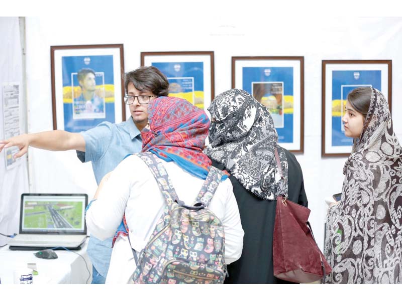 a student explains his artwork to visitors at uop photo express