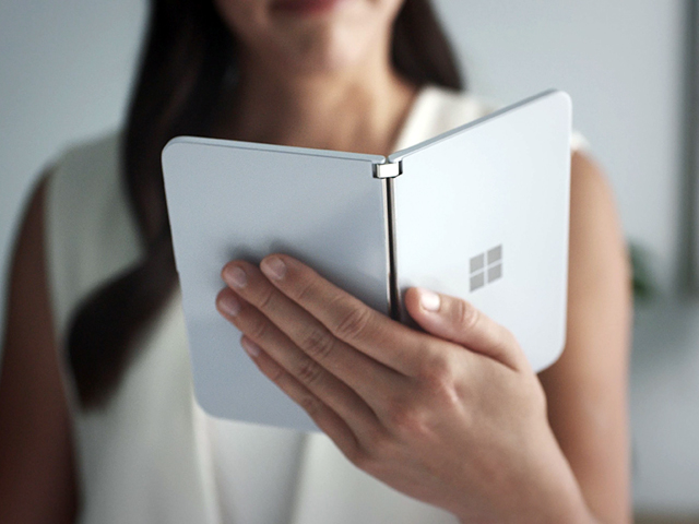 this handout photo obtained october 2 2019 courtesy of microsoft shows a woman looking at a new dual screen device surface duo photo afp