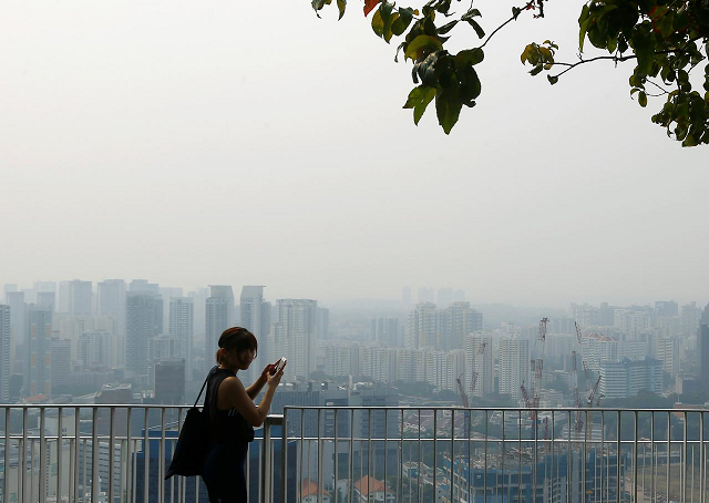 a woman uses her phone on an observation deck as the skyline shrouded by haze is seen in singapore september 13 2019 photo reuters