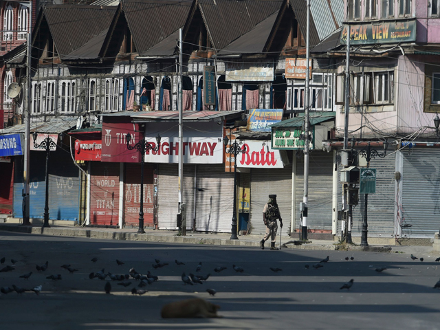 in this file photo taken on september 8 2019 an indian paramilitary trooper patrols along an empty street during a strict curfew in srinagar photo afp