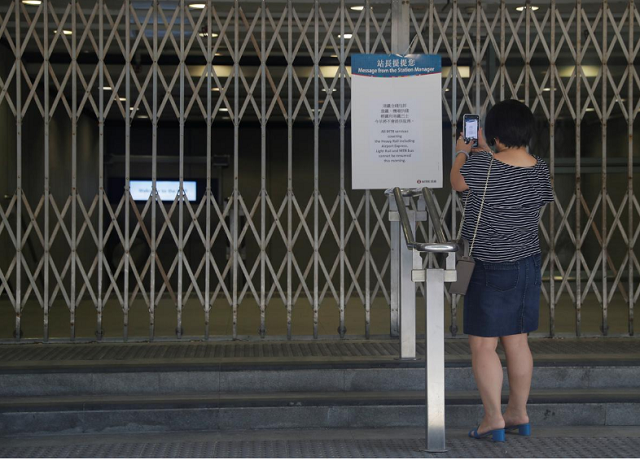 a woman takes a picture of an information board at the suspended metro station in tsim sha tsui district in hong kong china photo reuters