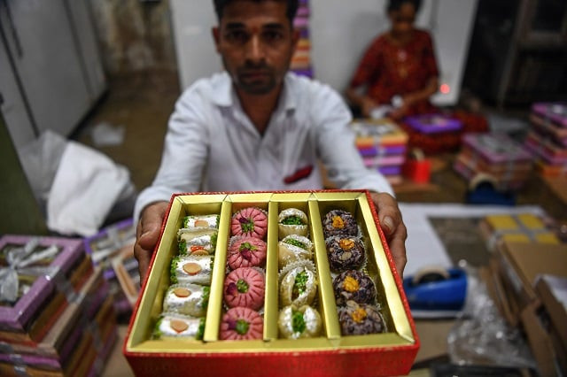 a worker holds up a gift box of sweets being packed at a factory in mumbai photo afp a worker holds up a gift box of sweets being packed at a factory in mumbai photo afp