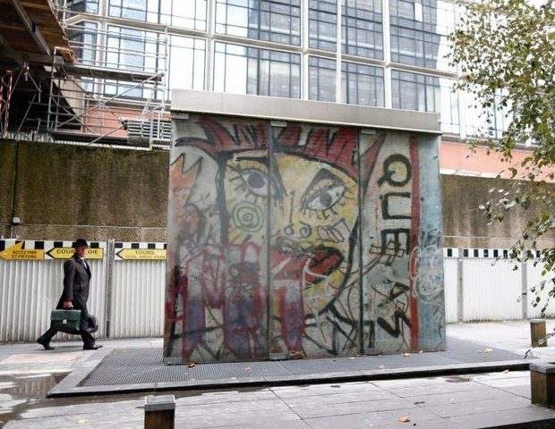 a man walks near a piece of the berlin wall depicting german artist and musician kiddy citny in the la defense business district in courbevoie photo reuters