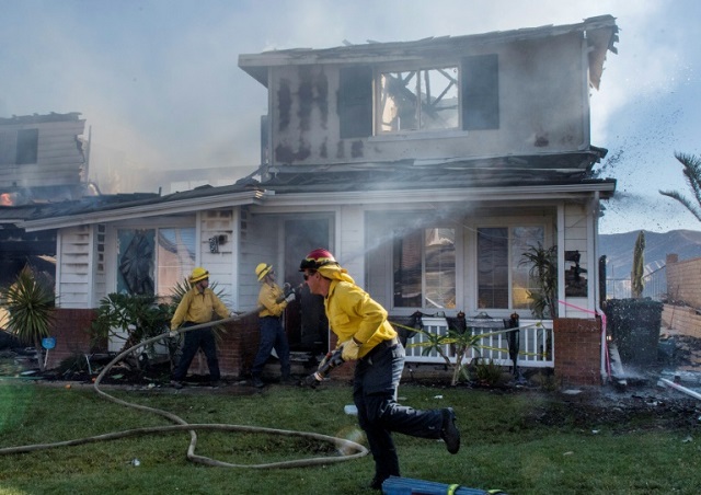 firefighters hose down a burning house during the tick fire in agua dulce near santa clarita california on october 25 2019 photo afp
