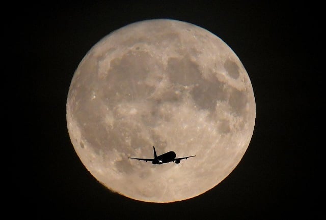 a passenger plane is seen with the full moon behind as it begins its final landing approach to heathrow airport in london britain september 24 2018 photo reuters