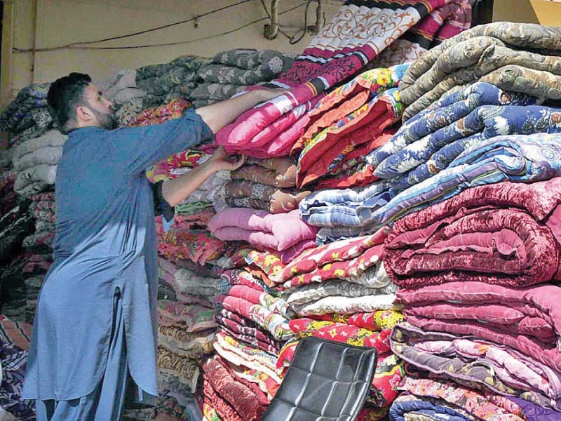 a shopkeeper arranges cotton filled quilts at his shop in islamabad photo app
