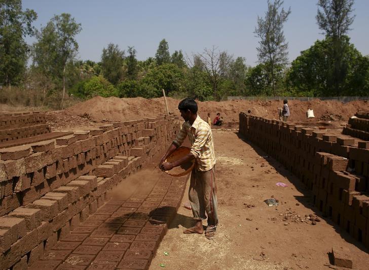 a labourer throws mud on bricks kept for drying at a kiln photo reuters