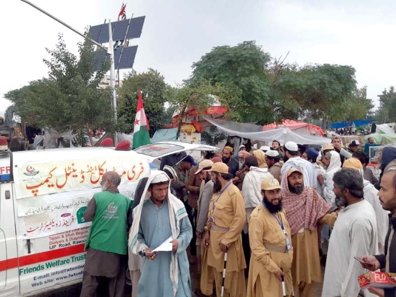 azadi march participants queue up at a free medical camp while cda officials use an excavator in a clean up operation at the protest camp site photos express