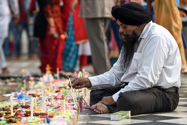 a sikh devotee lights candles as he pays his respect on the occasion of the 550th birth anniversary of sikhism founder guru nanak dev photo afp