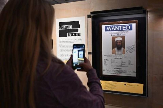 a woman takes a picture of an osama bin laden wanted poster at the quot revealed the hunt for bin laden quot exhibition at the national 9 11 memorial museum photo afp