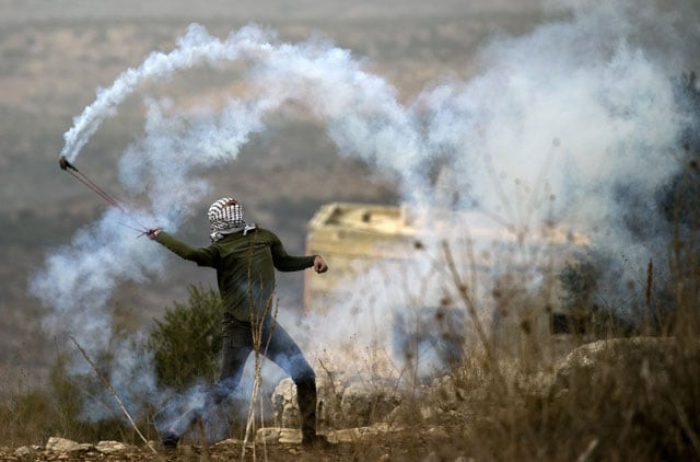 a palestinian protester uses a slingshot to return a tear gas canister fired by israeli forces on friday photo afp a palestinian protester uses a slingshot to return a tear gas canister fired by israeli forces on friday photo afp