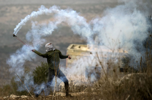 a palestinian protester uses a slingshot to return a tear gas canister fired by israeli forces on friday photo afp