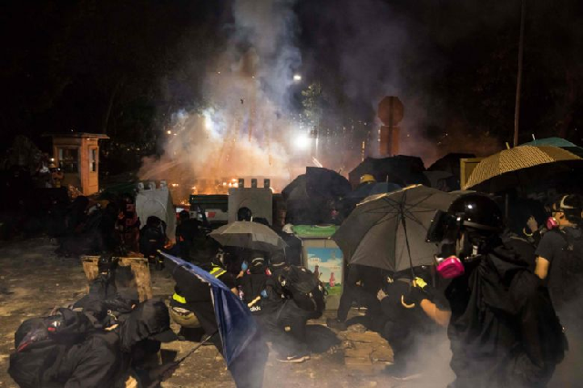 protesters shelter behind their barricade during clashes with police at the chinese university of hong kong photo afp