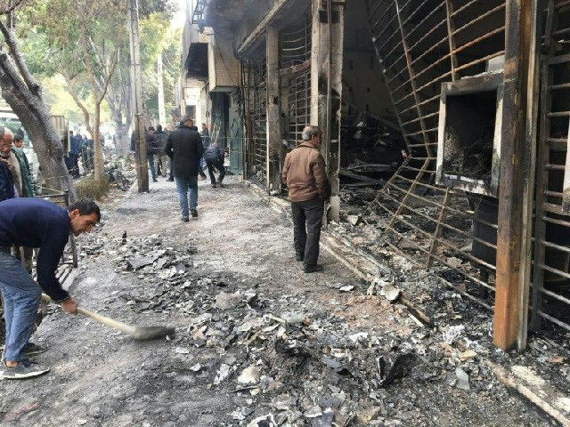 iranians walk past a bank that was set on fire by protesters during a demonstration against a rise in gasoline prices in isfahan on november 17 photo afp