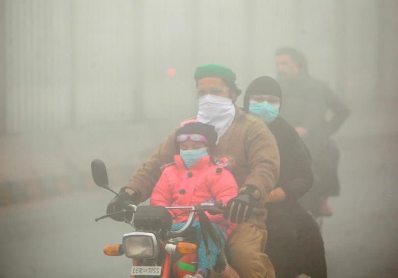 people use face masks to protect themselves from morning smog as they ride on bike along a road in lahore november 10 2017 photo reuters file