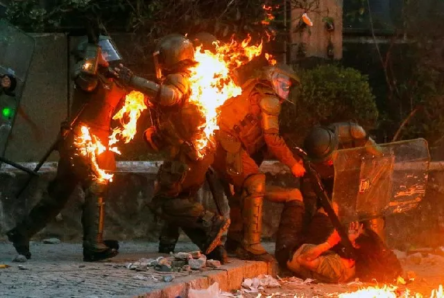 a demonstrator is held while a petrol bomb hits riot police during a protest against the government in santiago photo afp a demonstrator is held while a petrol bomb hits riot police during a protest against the government in santiago photo afp