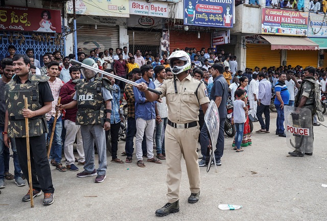 police officers stand guard as people attend a protest against the alleged rape and murder of a 27 year old woman in shadnagar on the outskirts of hyderabad india photo reuters