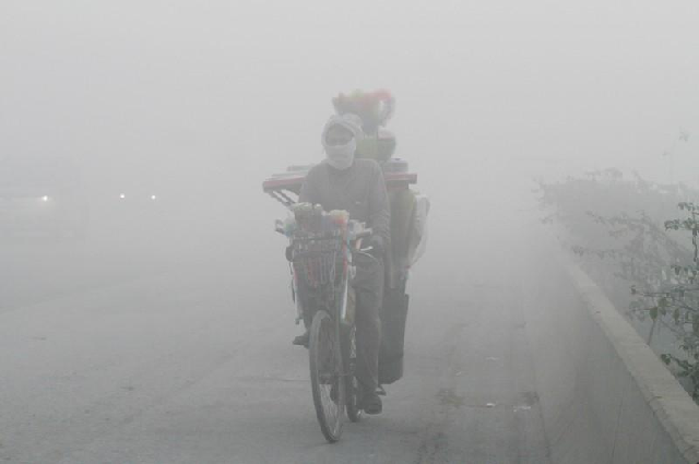 a man rides a bicycle on a smoggy morning in lahore photo reuters