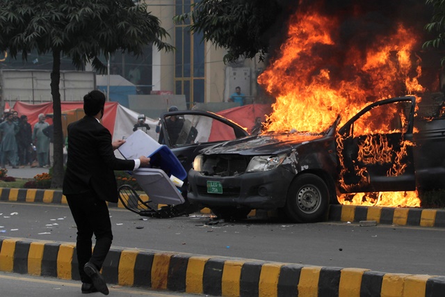 a lawyer throws trash bin towards police near a vehicle set on fire outside the punjab institute of cardiology pic in lahore photo reuters