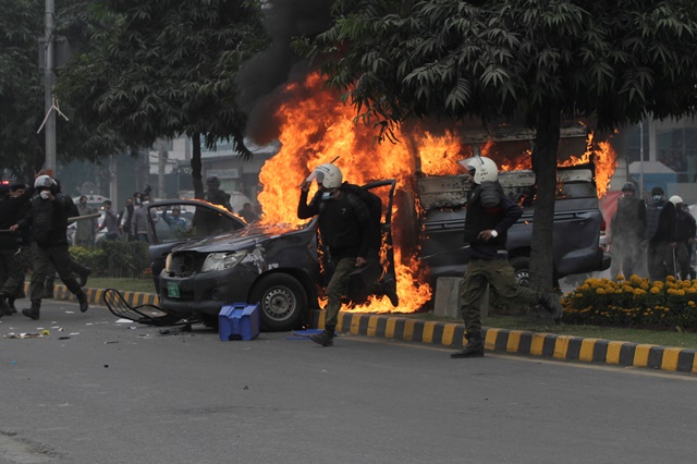 police officers run past a vehicle on fire after a group of lawyers stormed the punjab institute of cardiology photo reuters