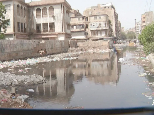a road lost to neglect sewage water garbage piles and stray dogs make a central karachi route impassable risking health and safety photo express