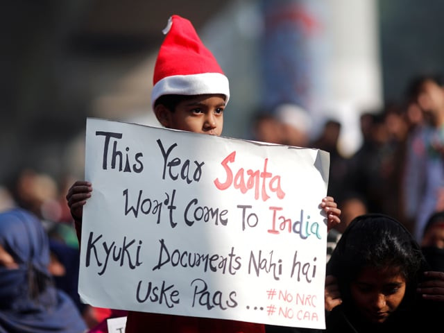 a girl wearing a santa claus hat holds a placard as she attends a protest against a new citizenship law outside the jamia millia islamia university in new delhi india december 25 2019 photo reuters