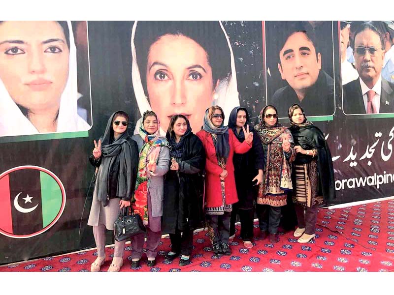 women pose infront of a large party poster in liaquat bagh on friday photo nni