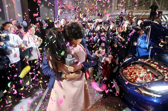 a tesla employee proposes to his girlfriend with a china made tesla model 3 vehicle filled with flowers at a delivery ceremony in the shanghai gigafactory of the us electric car maker in shanghai china december 30 2019 photo reuters