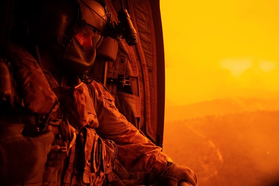 warrant officer class two darrel rowe from the 5th aviation squadron searches the ground from an australian army ch 47f chinook during the flight to omeo victoria australia to evacuate local civilian residents during operation bushfire assist photo reuters