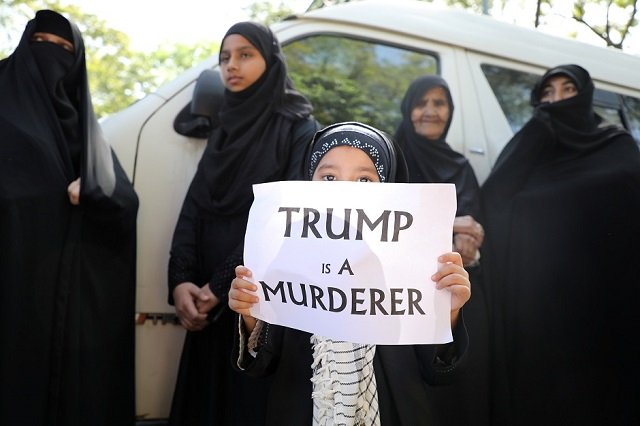 a girl holds a sign saying quot trump is a murderer quot during a condolence ceremony for iranian major general qassem soleimani photo reuters