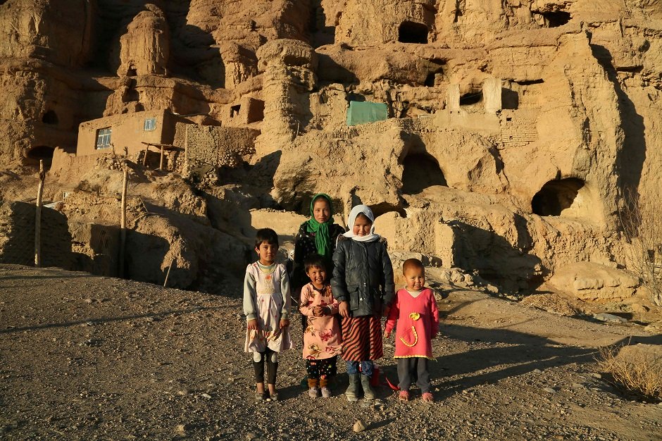 hazara children in front of caves where they live with their family in bamiyan   after bearing the brunt of jihadist dynamite and looting by thieves the archaeological treasures of afghanistan s bamiyan province are facing a new and possibly more daunting threat climate change photo afp