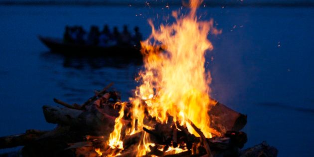 a tourist boat goes past the burning flames of a pyre at a cremation ground on the banks of river ganges in varanasi photo reuters