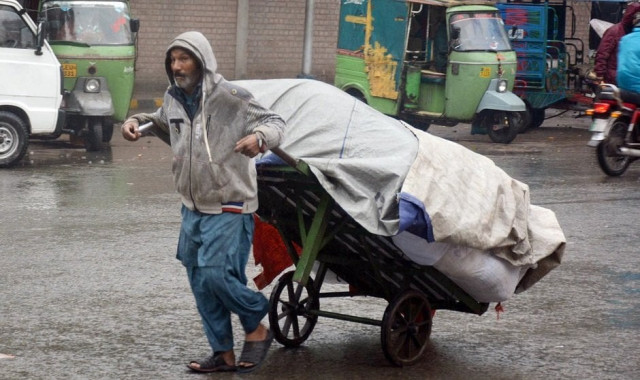 a labor carries a loaded wheelbarrow during a rain spell in lahore photo file a labor carries a loaded wheelbarrow during a rain spell in lahore photo file