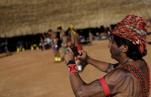 an indigenous man films a performance during a four day pow wow in piaracu village in xingu indigenous park near sao jose do xingu mato grosso state photo reuters
