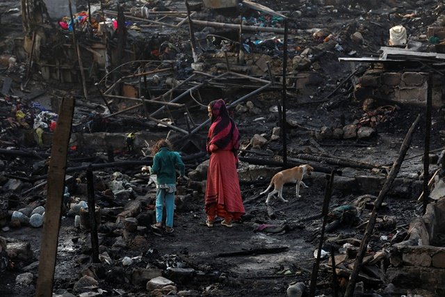 siblings with their pet dog search for belongings as they visit the burnt out house of their family after a fire broke out in a slum in karachi reuters