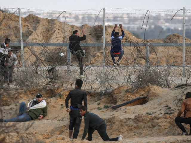 palestinian demonstrators climb a section of a fence at the israel gaza border east of rafah in the southern gaza strip during a protest on december 27 2019 photo afp