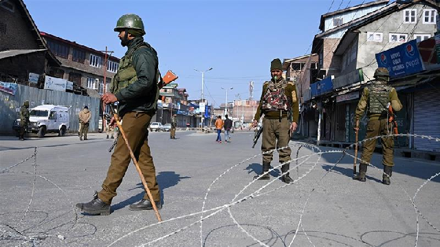 indian paramilitary trooper stands guard at a checkpoint during a one day strike called by jammu and kashmir libration front jklf to demand the return of the remains of afzal guru photo afp