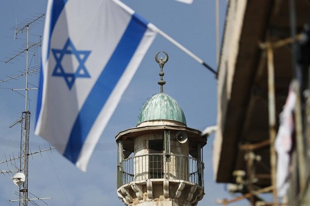 an israeli flag waves in front of the minaret of a mosque in the arab quarter of jerusalem 039 s old city photo afp