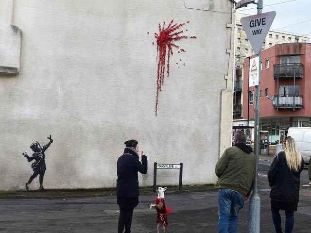the graffiti shows a young girl in a headscarf with a catapult and a splatter of red flowers photo reuters the graffiti shows a young girl in a headscarf with a catapult and a splatter of red flowers photo reuters