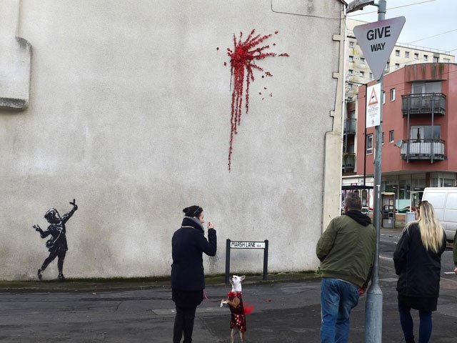 the graffiti shows a young girl in a headscarf with a catapult and a splatter of red flowers photo reuters