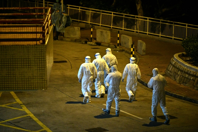 hong kong medical personnel wearing protective suits walk in a residential estate after two people in the block were confirmed to have contracted the new coronavirus according to local newspaper reports photo afp