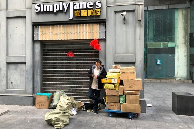 a man wearing a face mask checks his mobile phone next to a trolley of boxes on the streets of huaqiangbei the world 039 s largest electronics market following an outbreak of the novel coronavirus in the country in shenzhen guangdong province china february 18 2020 photo reuters