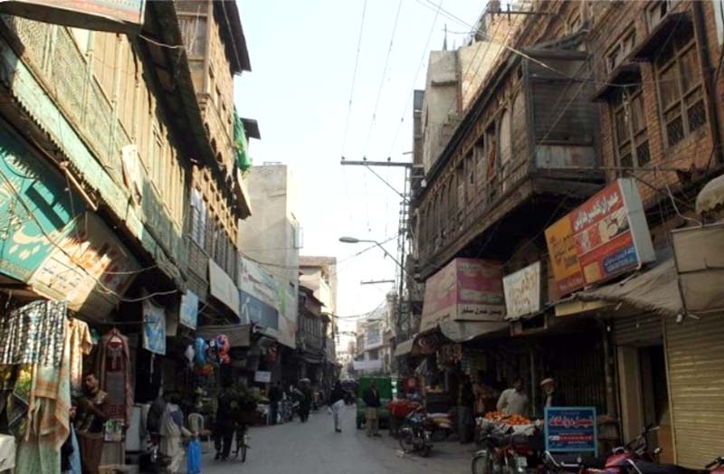 people walk along on a street in the old city area of rawalpindi where some buildings date back to british era photo express