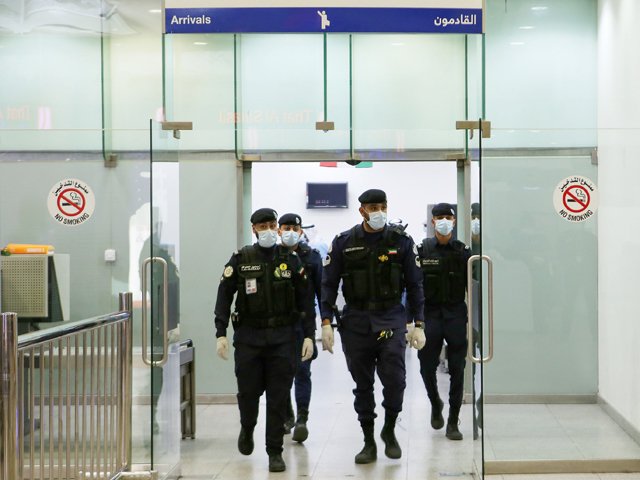 kuwaiti policemen wearing protective masks wait at sheikh saad airport in kuwait city on february 22 2020 before transferring kuwaitis arriving from iran to a hospital to be tested for coronavirus photo afp