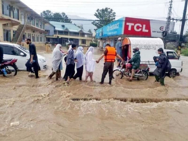 rescue officials help women cross a flooded road in abbottabad photo ppi rescue officials help women cross a flooded road in abbottabad photo ppi