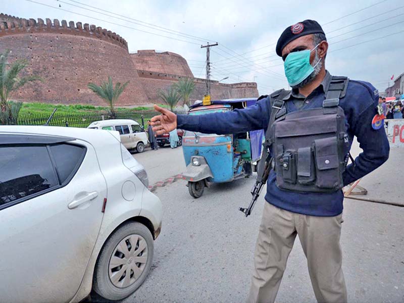 a cop wears a facemask at a check post outside the bala hissar fort in peshawar on friday photo inp