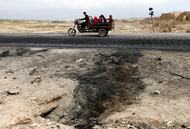 an afghan family ride on a bike past the site of a car bomb attack where us soldiers were killed near bagram air base afghanistan april 9 2019 photo reuters