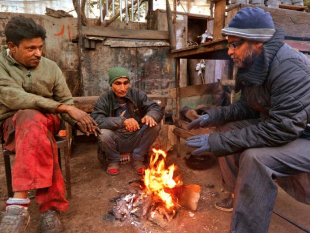 mechanics chat as they sit around a fire during a lean hour at their workshop in a karachi neghbourhood on thursday photo jalal qureshi mechanics chat as they sit around a fire during a lean hour at their workshop in a karachi neghbourhood on thursday photo jalal qureshi