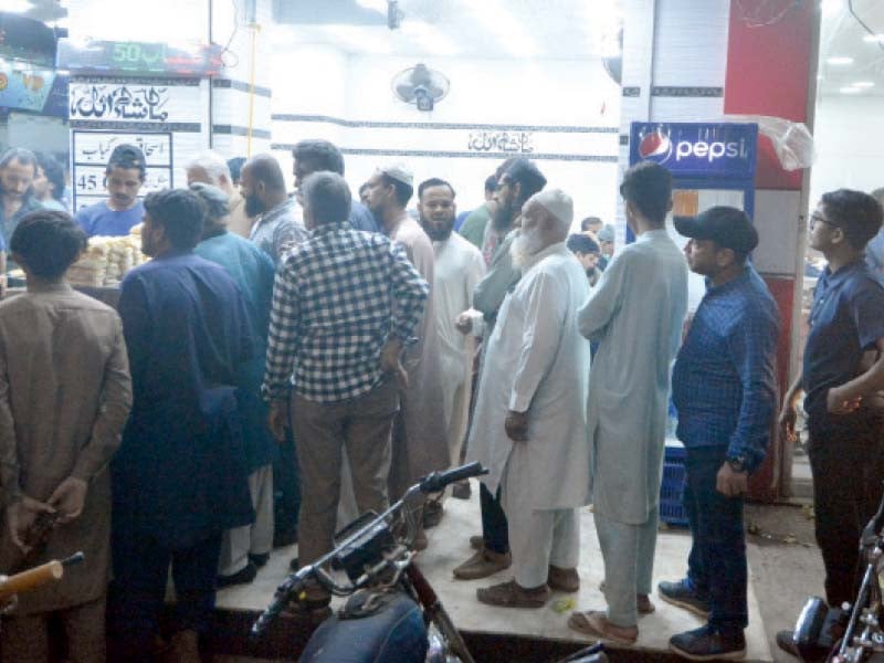 people stand in a queue on a footpath to by bun kebabs from a shop on burns road food street photo jalal qureshi express